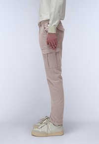 Světlé béžové cargo kalhoty s bočními kapsami, slim fit a mírně zúženými nohavicemi, doplněné o krémové tenisky a světle barevný svetr.