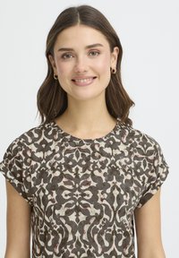 Barna és krémszínű mintás felső rövid, felhajtott ujjakkal, virágos damaszt mintával és puha textúrával.