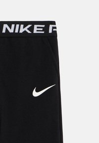 Black sweatpants with a white Nike logo. Features a ribbed waistband with "NIKE" in white. Material appears soft and textured.