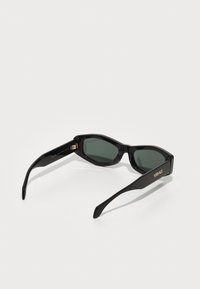 Gafas de sol negras con un diseño elegante, con lentes verdes, detalles en dorado y un acabado brillante en las monturas. Marca Versace en la pata.