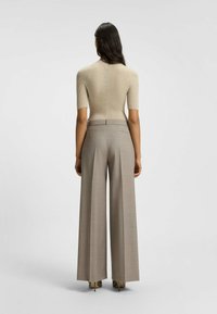 Top corto a maniche corte in maglia a righe beige abbinato a pantaloni a palazzo larghi beige con stampa plaid a vita alta, che mostrano una texture liscia e una vestibilità su misura.