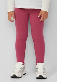 Leggings di cotone rosa con una vestibilità aderente, una trama liscia e un design semplice. Abbinati a scarpe da ginnastica bianche e grigie.