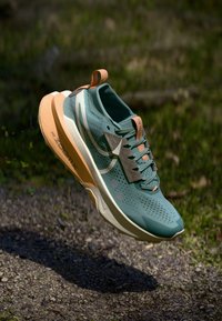 Lichtblauw sportief schoen met geperforeerde bovenkant, oranje accenten en een gevoerde zool. Bevat een gestructureerd oppervlak en een vetersluiting.