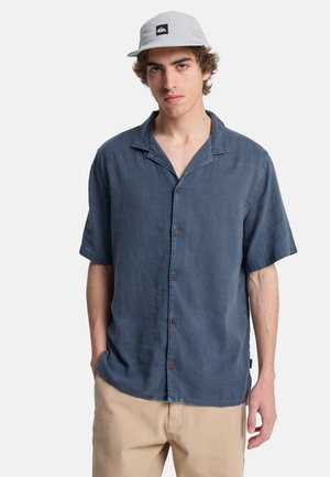 Kurzärmeliges Hemd zum Knöpfen aus dunkelblauem Stoff mit lockerer Passform. Verfügt über einen verbreiterten Kragen und braune Knöpfe. Glatte Textur.