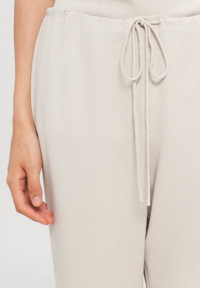 Lichtbeige joggers van zachte stof met een trekkoord in de taille, met een gladde textuur en een lichte glans.