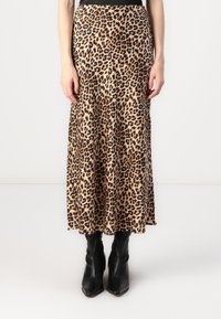 Maxiskjørt i leopardmønster av glatt stoff, med svart midje. Kombinert med tettsittende svarte ankelstøvler for kontrast.