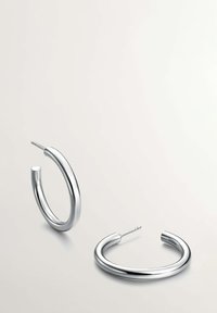 Pendientes de aro de plata con una textura suave y pulida, que presentan un diseño circular moderno y un mecanismo de cierre seguro en la parte posterior.
