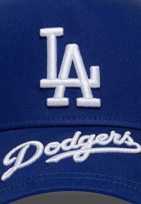 Casquette de baseball bleue avec logo "LA" brodé en blanc et script "Dodgers". Tissu lisse avec une couronne structurée et une visière incurvée.