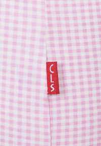 Tkanina bawełniana w różowo-białą kratkę. Posiada czerwoną metkę z napisem "CLS" w białym kolorze. Gładka faktura.