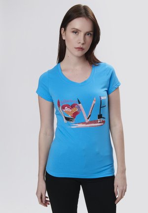 T-shirt ajusté bleu clair à manches courtes présentant un design graphique multicolore d'articles de maquillage et le mot "AMOUR" dans un style décoratif.
