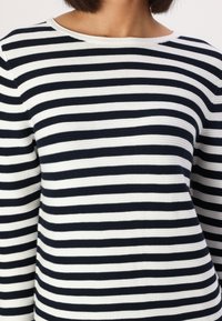 Gestreiftes Langarmoberteil in Weiß und Marineblau, mit geripptem Material und rundem Halsausschnitt. Streifen gleicher Breite verlaufen horizontal.