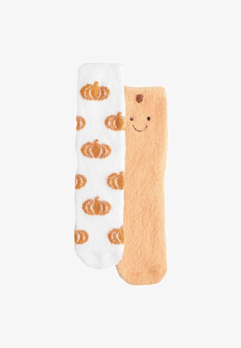 Ein Paar flauschiger Socken, eine weiß mit orangefarbenen Kürbismustern, die andere hellorange mit einem lächelnden Gesicht oben.