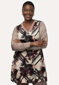 Wzorzysta tunika z dekoltem w kształcie litery V, ozdobiona kwiatowymi wzorami w odcieniach fioletu, czerni i neutralnych; długie, jednokolorowe rękawy z teksturowanymi mankietami.