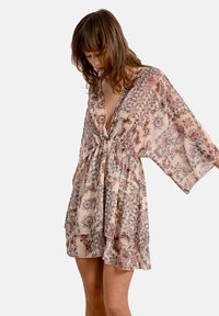 Abito kimono a fantasia floreale in beige chiaro, con scollatura a V profonda, maniche ampie e vita legata per un fit rilassato.