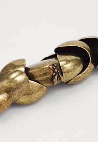 Bronse kjede med sammenflettede blomsterblad-formede lenker, med en teksturert overflate og en liten sommerfugldetalj på en av lenkene.