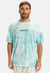 Light blue tie-dye T-shirt with short sleeves, made of soft fabric. Features the "Quiksilver" logo in dark text on the chest.