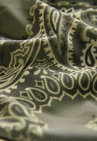 Vzorovaná látka v tlmenej olivovozelenej farbe s precízne navrhnutými krémovými paisley vzormi, s textúrovaným povrchom a jemným padaním.