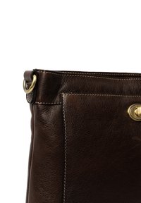 Borsa a mano in pelle marrone scuro con finitura testurizzata, dotata di una tasca con zip orizzontale e un accento in ottone. Dettaglio di cucitura minimale.