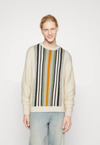 Pull en tricot crème avec des rayures verticales multicolores, y compris du vert, du bleu marine et de l'orange. Doté d'un col rond et d'une coupe décontractée.
