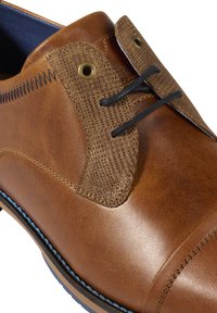Scarpa in pelle marrone con pannello in tessuto a trama, lacci neri e occhielli in ottone. Finitura liscia con dettagli di cucitura blu in contrasto.