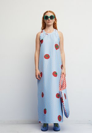 Sukienka maxi w niebiesko-białe paski, z czerwonymi nadrukami pomidorów i okrągłym dekoltem. Dodatkiem jest czerwona i biała kraciaste torba na ramię.