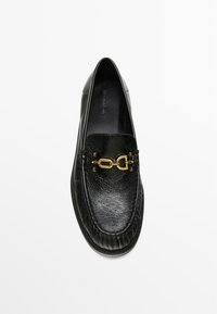 Zwarte leren loafers met een gestructureerde afwerking, voorzien van een gouden kettingaccent aan de voorkant en een rondothe ontwerp. Gladde binnenvoering.