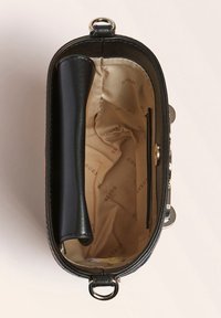 Sort læderhåndtaske med beige stofforing trykt med "GUESS" og et lille indvendigt lynlåslomme, vist fra oven.