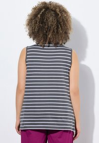 Canottiera grigia a righe con strisce bianche, design senza maniche, tessuto morbido, vestibilità comoda, orlo arrotondato, indossata con pantaloni viola.