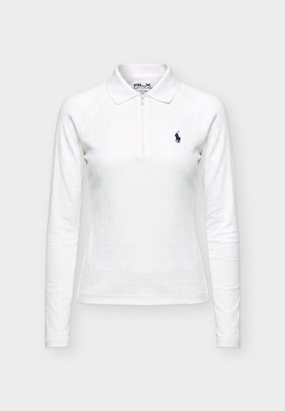 Polo blanc à manches longues avec une fermeture éclair quart de tour, tissu texturé et un petit logo joueur de polo bleu marine sur le côté gauche de la poitrine.