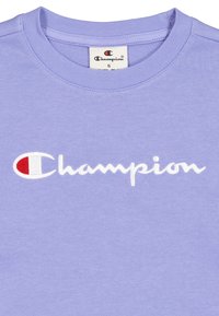 Pullover in lavanda realizzato in tessuto misto cotone, con logo "Champion" ricamato in bianco con un accento rosso sulla sinistra.