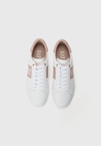 Beli športni copati s svetlo roza detajli, ki imajo gladko usnjeno zgornje delo, ravne vezalke, zlato logotipno podrobnost in okroglo obliko prstov.