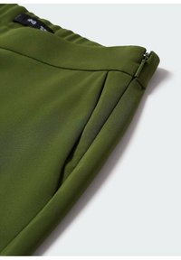 Groene stof met een gladde textuur en een slank ontwerp, met een zijritsdetail en geplooide accenten langs de tailleband.