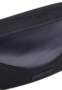 Pochette en tissu noir avec un intérieur lisse et une fermeture éclair. Présente un patch logo discret. Forme compacte et rectangulaire.