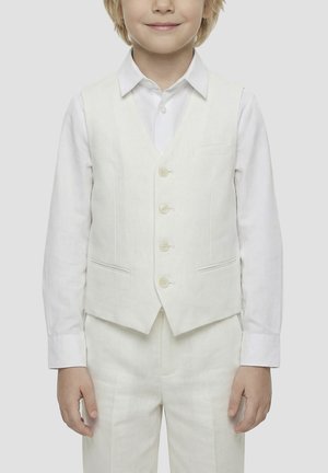 Niño joven que lleva una camisa blanca de vestir, un chaleco blanco abotonado y pantalones blancos a juego sobre un fondo claro y liso.