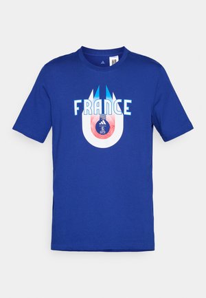 Zils kokvilnas T-krekls ar vārdu "FRANCIJA" baltā krāsā, zem kura ir apļa grafika, kas attēlo futbolu un logotipu sarkanā un zilā krāsā.