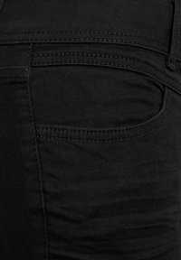 Mustat farkut, joissa on sileä pinta, hillitty ommel ja klassinen taskusuunnittelu, sekä slim fit -leikkaus.