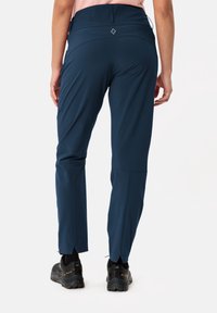 Navy performance pants with a fitted design, elastic waistband, and zippered cuffs. Made of lightweight, durable fabric.