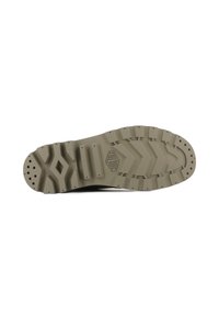 Semelle de chaussure en caoutchouc avec un design texturé et dentelé en beige clair, comportant des trous de drainage circulaires et en forme de losange ainsi qu'un détail de marque.