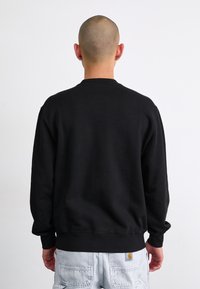 Black cotton sweatshirt with a crew neckline, ribbed cuffs, and hem. The fabric appears smooth with no visible graphics or patterns.