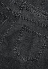 Jeans de denim negro con un acabado texturizado, diseño tradicional de cinco bolsillos y costuras prominentes a lo largo de las costuras y los bolsillos.