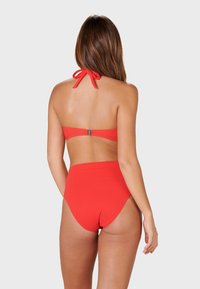 Red bikini featuring a halter neck design with a tied bow and a high-waisted bottom for coverage. Smooth fabric with minimal hardware.