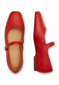 Bailarinas rojas de cuero con punta cuadrada, tira en el tobillo y tacón bajo. Textura suave y diseño minimalista con costuras visibles.