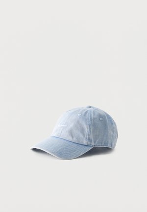 Casquette de baseball en denim bleu clair avec un logo Nike swoosh brodé en blanc sur le devant, posée sur un fond blanc uni.