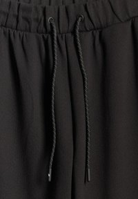 Ceinture élastique noire avec deux cordons noirs présentant une couture blanche subtile et des extrémités bouchées.