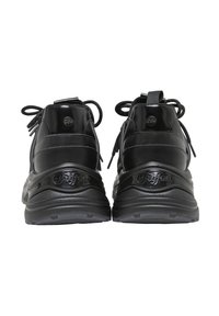 Paire de baskets noires de la marque Buffalo vues de dos avec des semelles épaisses et des lacets noués en nœuds.