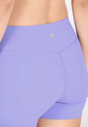 Lila hochtaillierte Shorts aus glattem Material mit einem goldenen Logoakzent auf der Rückseite und flachen Steppnähten in der Nähe der Nähte.