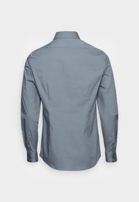 Camicia a maniche lunghe, di colore azzurro chiaro, realizzata in cotone morbido, con colletto standard, polsini con bottone e una vestibilità su misura con yoke posteriore.