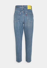 Ljusa blå högmidjade jeans i denim med rak bendesign, subtila slitningar och ikoniska bakfickor med sömnadsdetaljer.