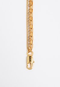 Pulsera de cadena de oro con un diseño de eslabones y piedras de strass transparentes. Incluye un cierre de langosta para un cierre seguro.
