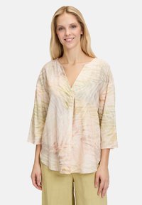 Blusa leggera a maniche corte con scollatura a V, caratterizzata da un motivo floreale pastello in tonalità di rosa, verde e giallo. Tessuto testurizzato.